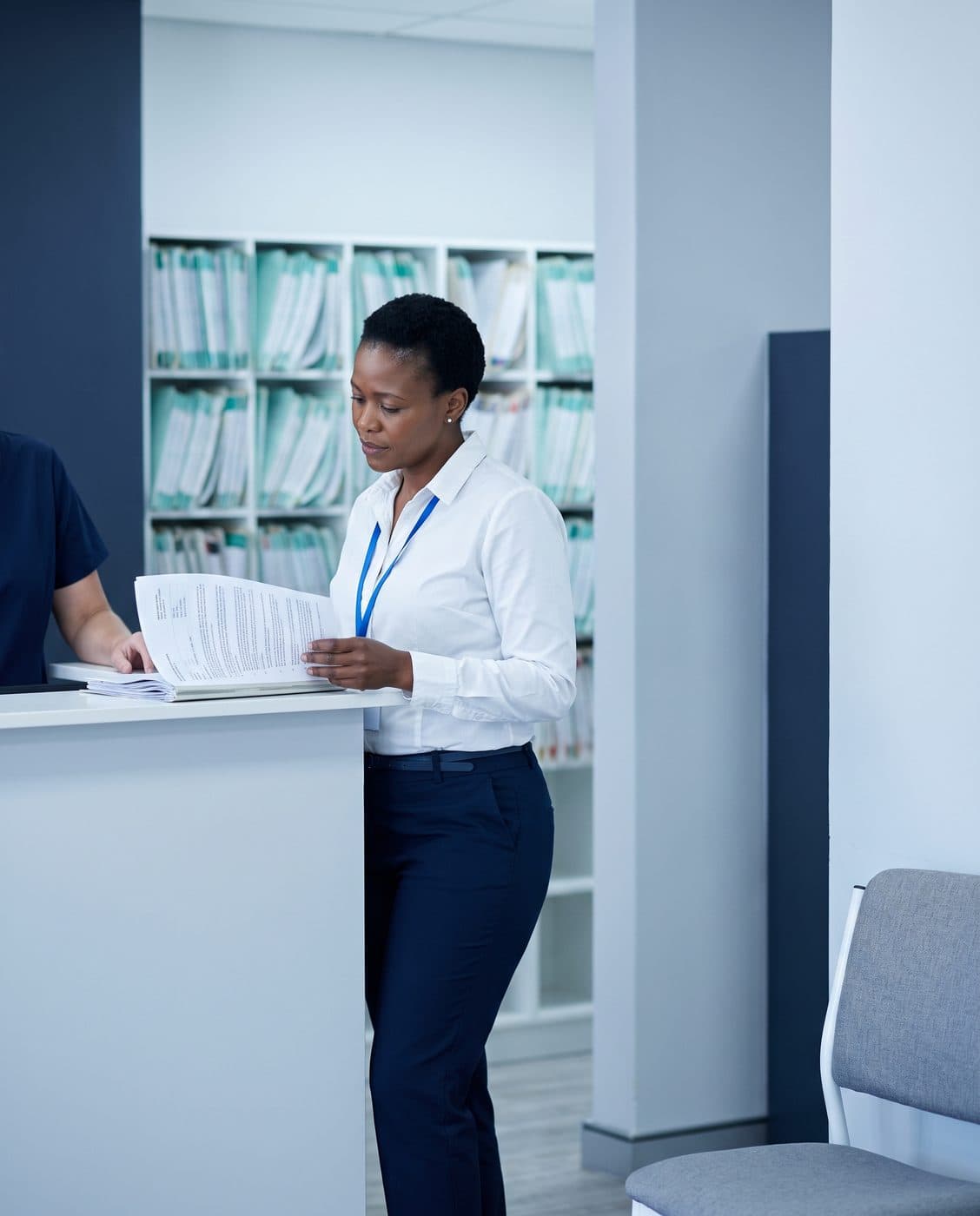 A practice manager reviewing a claims file at a medical practice reception counter